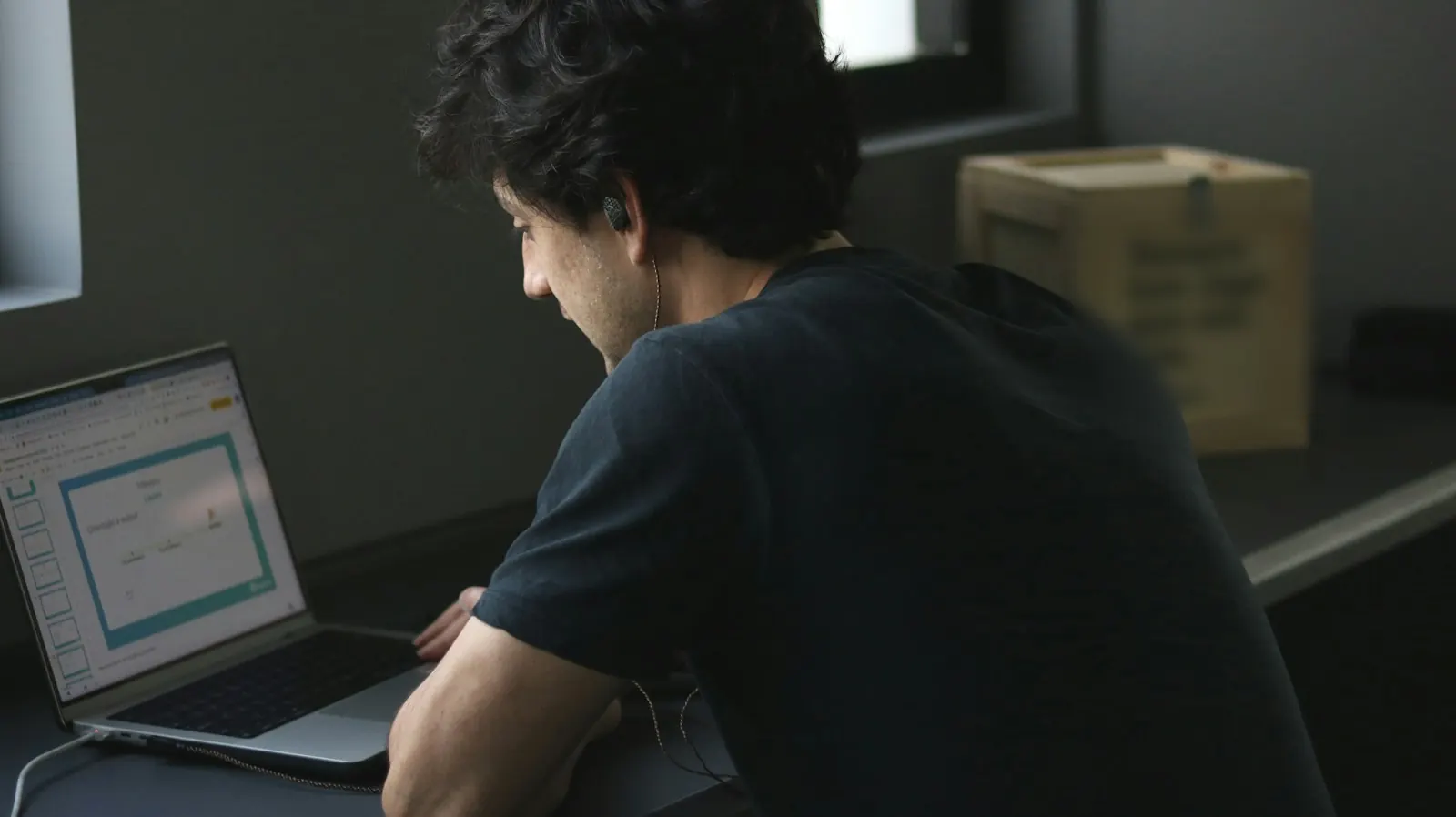 Eine Person arbeitet in einem schwach beleuchteten Büro am Laptop